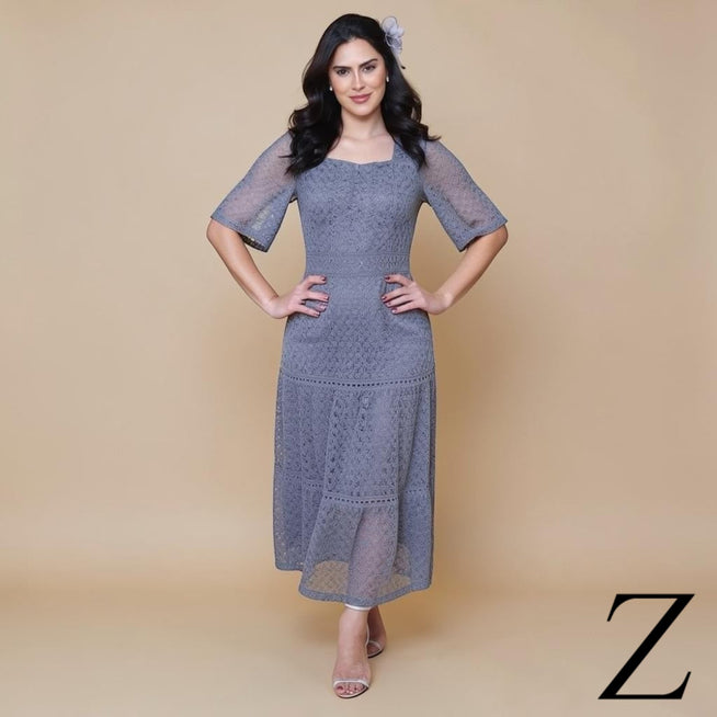 Modelo veste vestido longo ZAKRA cinza em crochê com decote quadrado, mangas curtas e detalhes em guipir elegante.